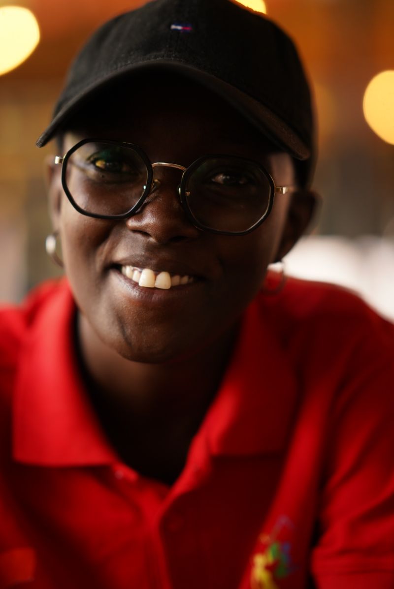 Juls smiling, wearing glasses and a black cap
